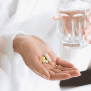 A woman holding pills and water